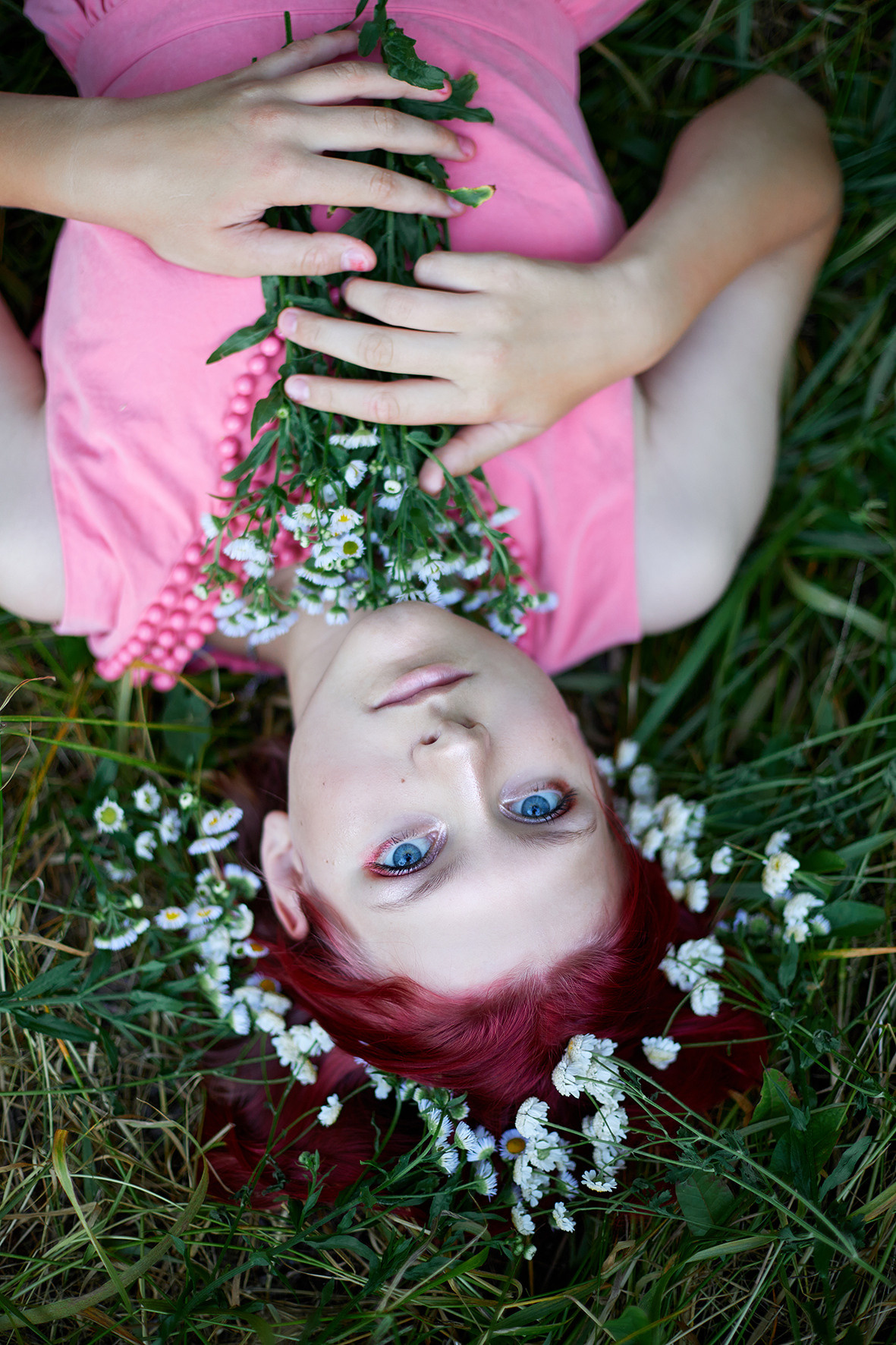 Портрет девушки в траве. Девушка в розовом платье с малиновыми волосами и венком из полевых цветов лежит на траве. Букет полевых цветов в руках девушки. Выразительные глаза. Фотограф. Тимашевск. Кубань. Краснодарский край.