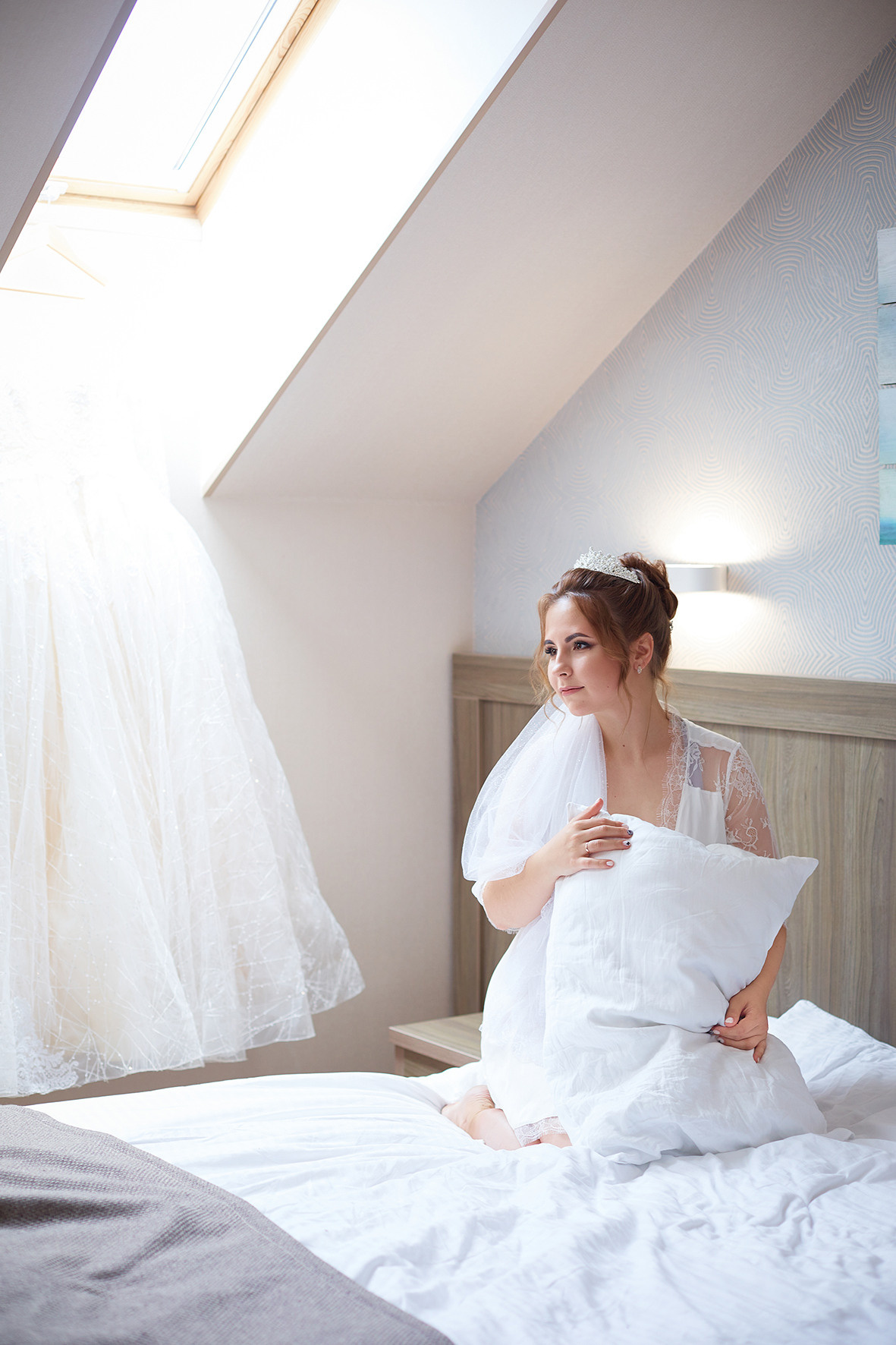 Утро невесты. Невеста в номере для новобрачных сидит на кровати с подушкой в руках. Потолочное окно. Фото в интерьере. Фотограф. Тимашевск. Кубань. Краснодарский край.