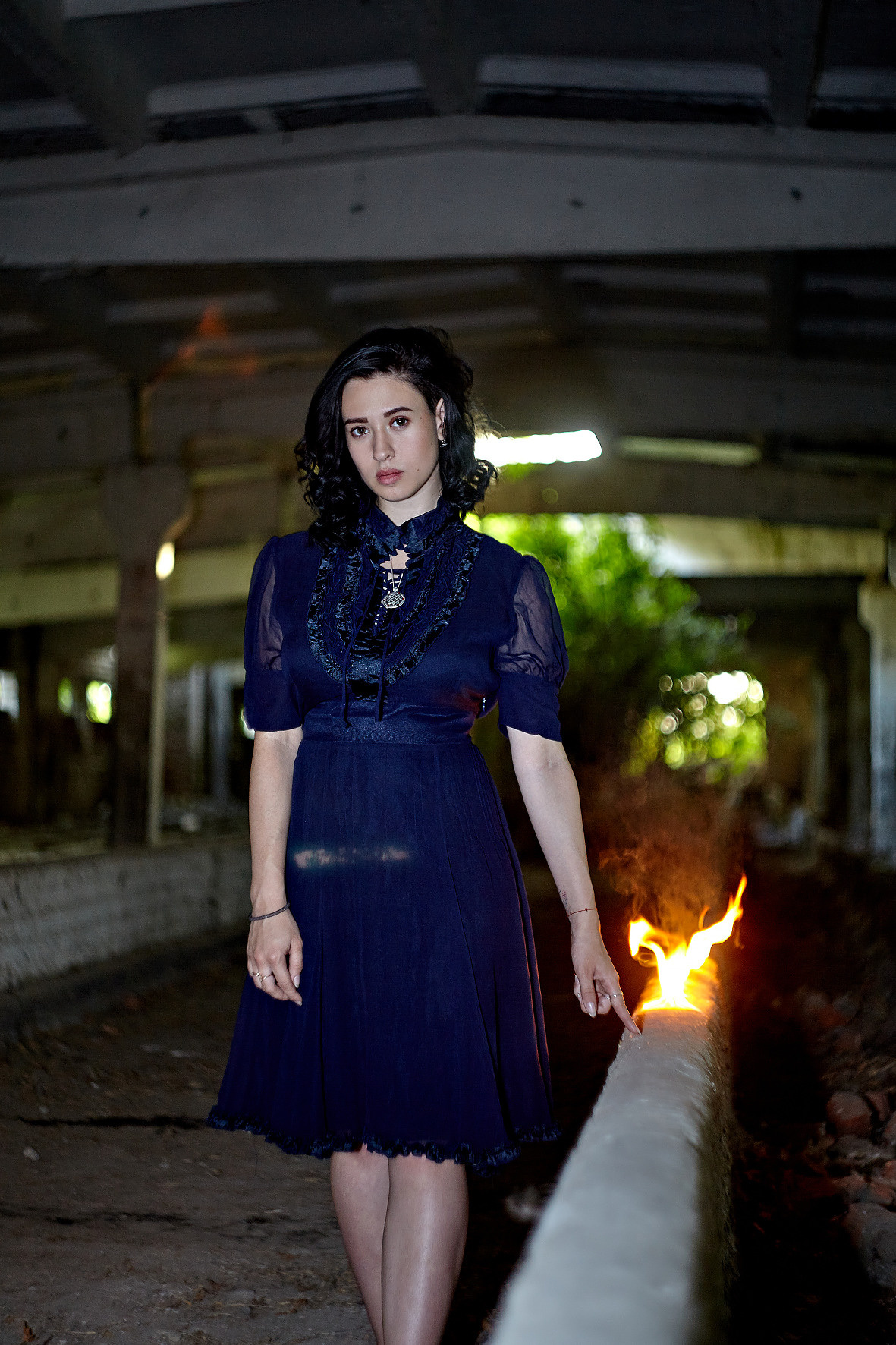 Девушка в синем платье в заброшенном здании идет вдоль бетонного ограждения и за ее рукой тянется огонь. Воспламеняющая девушка. Фотограф. Тимашевск. Кубань. Краснодарский край.