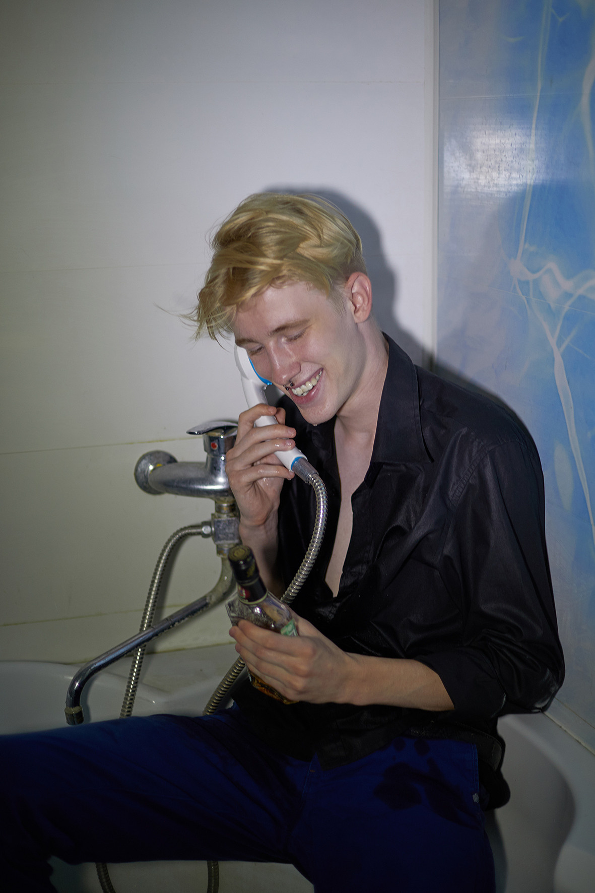 Парень в одежде в ванной разговаривает в душ как в телефонную трубку и собирается выпить коньяк. Фотограф. Тимашевск. Кубань. Краснодарский край.