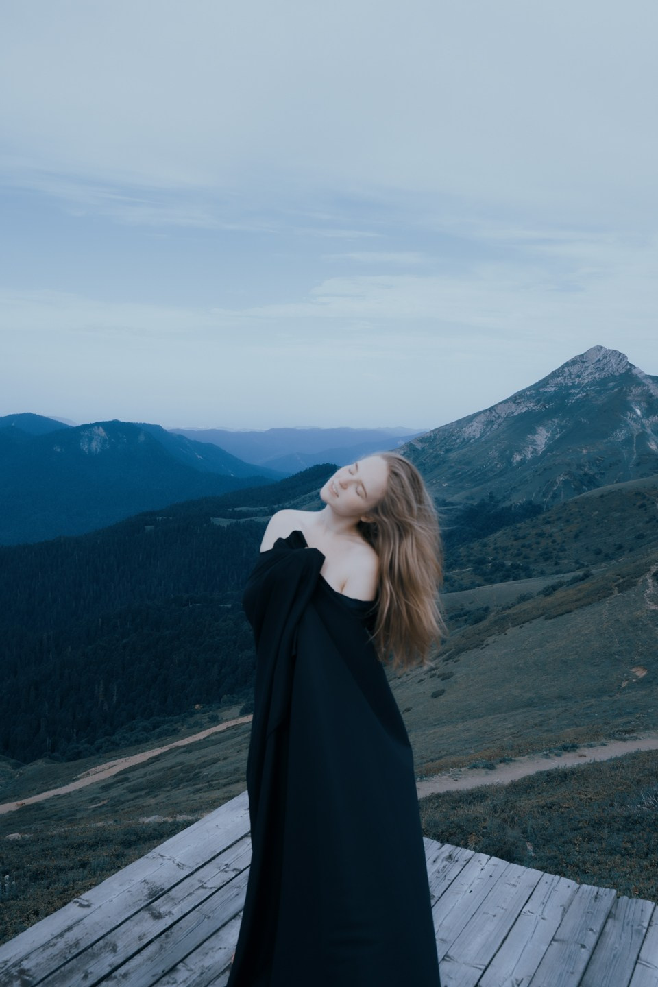 Снимок девушки на фоне горы в черном платье 