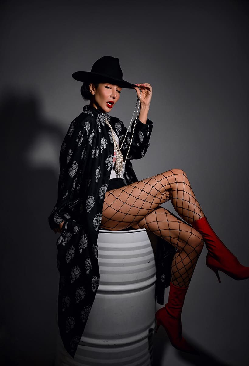 Женщина в шляпе поправляет рукой шляпу