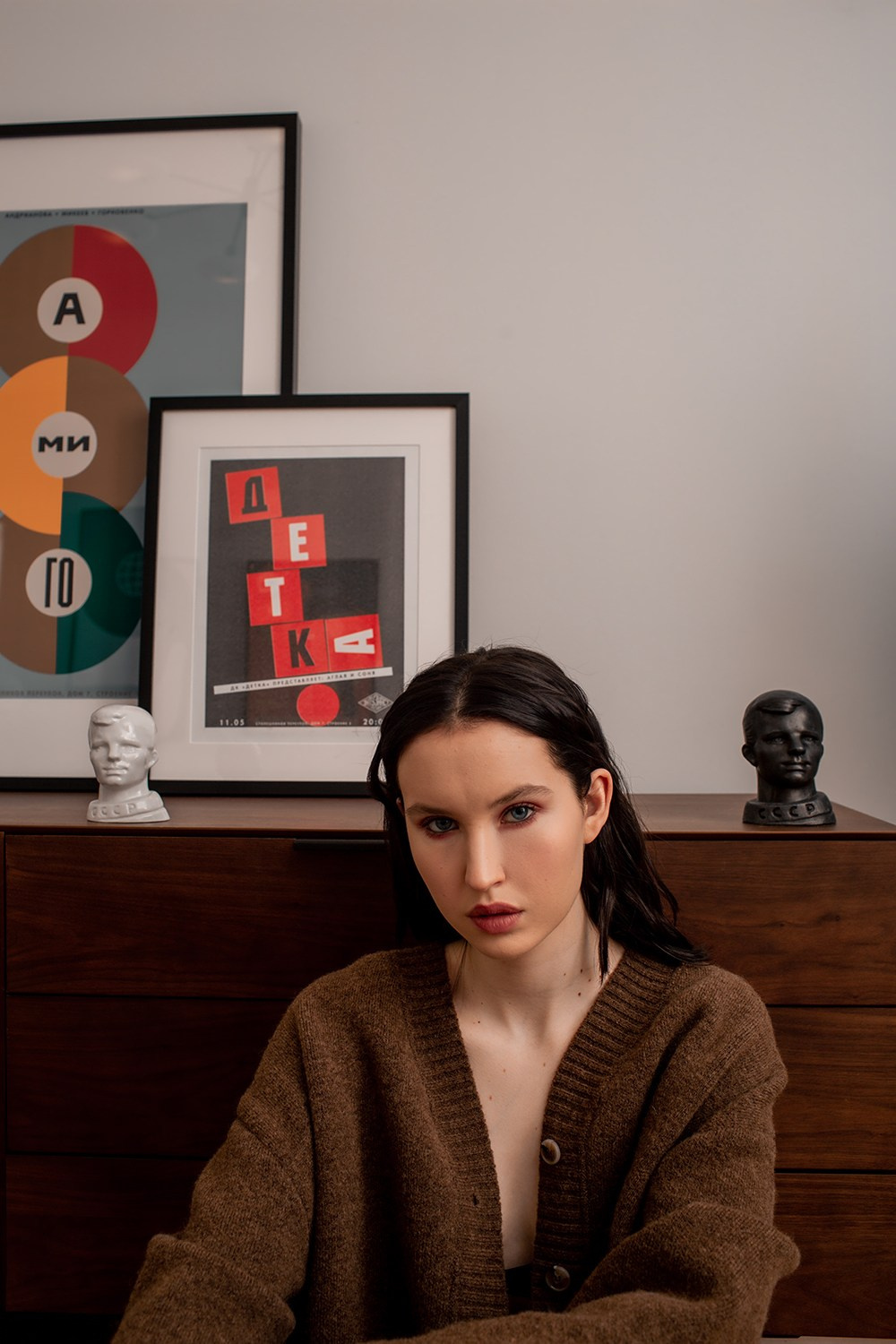 Девушка в свитере на фоне картин