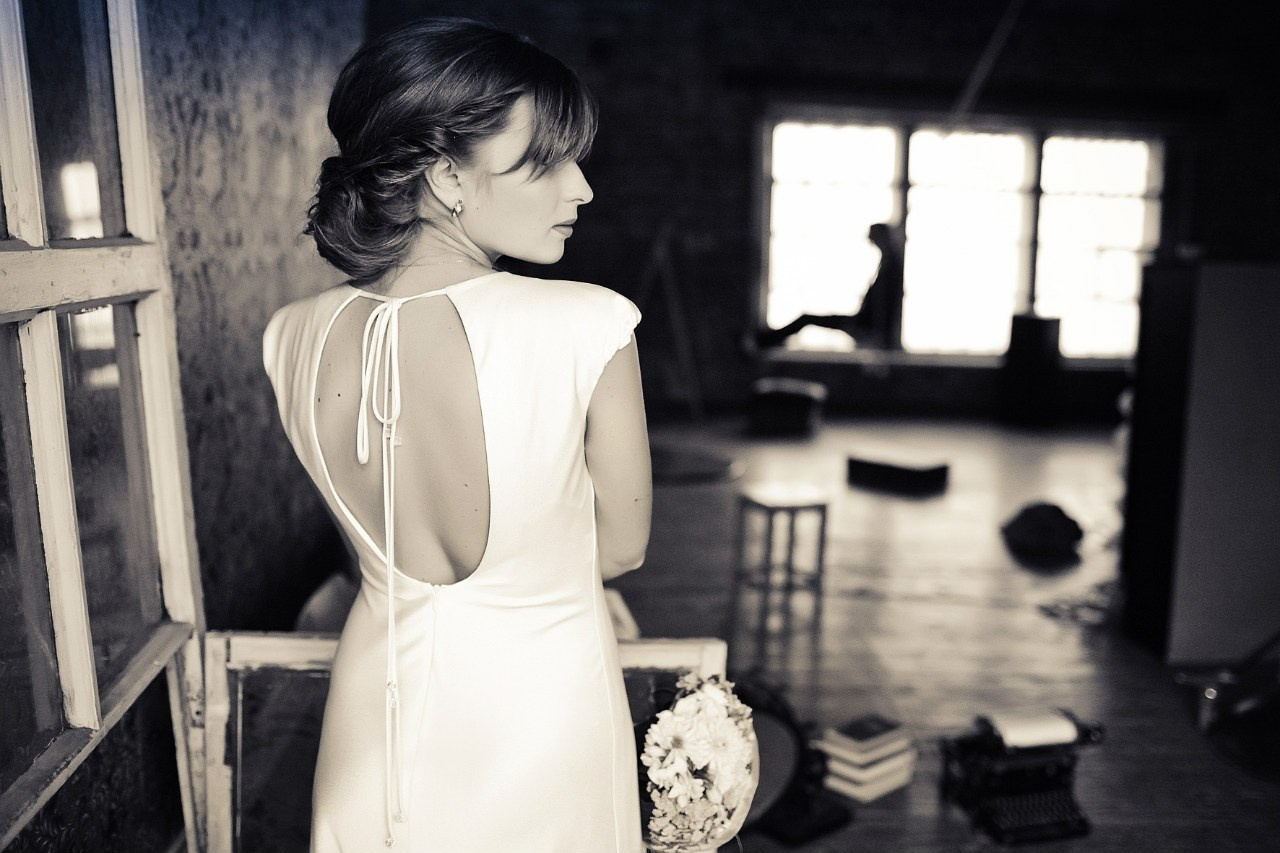женщина в белом платье с красивым вырезом на спине находится в просторной комнате