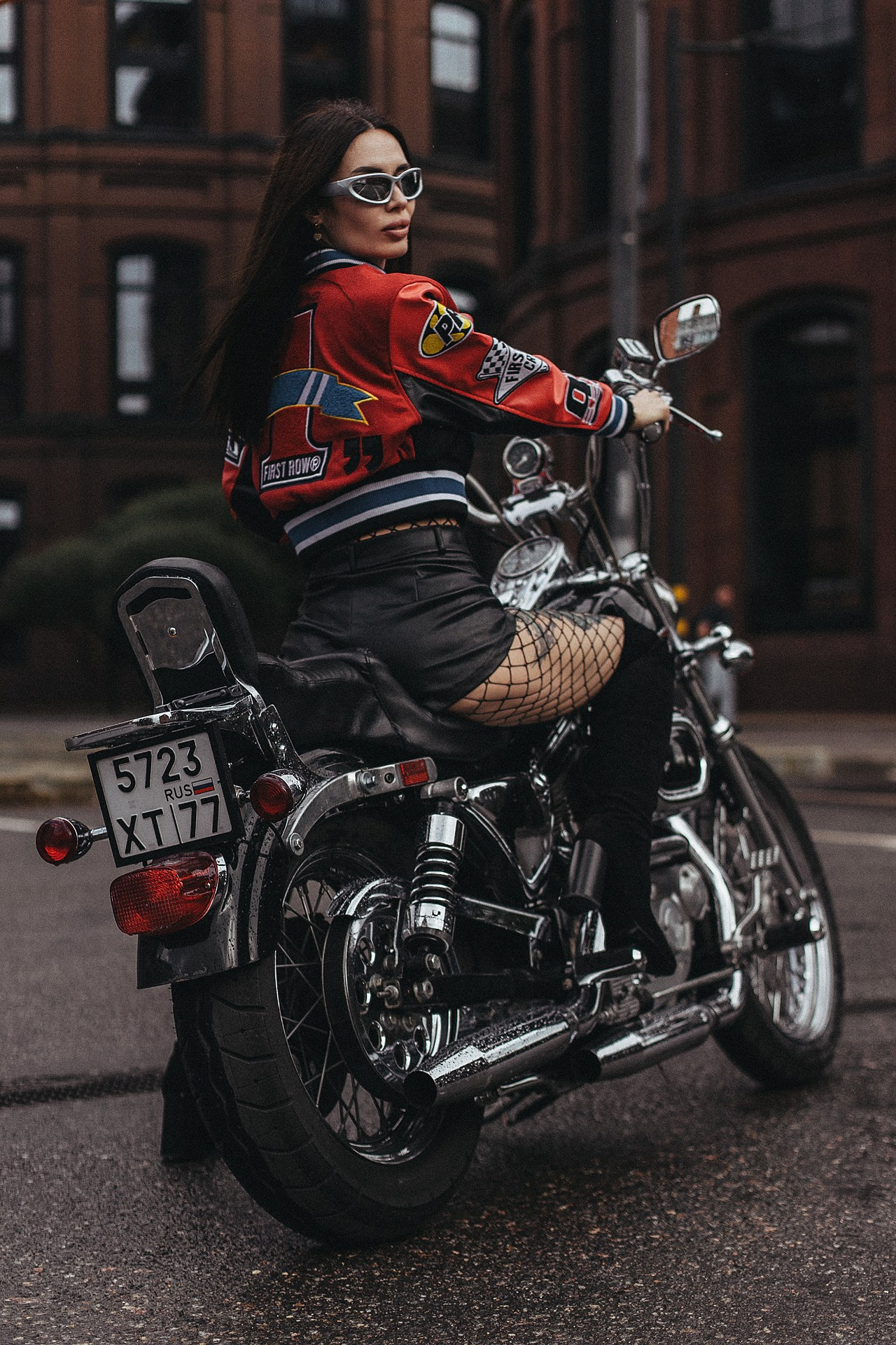 Девушка позирует с мотоциклом у современного здания в Москве