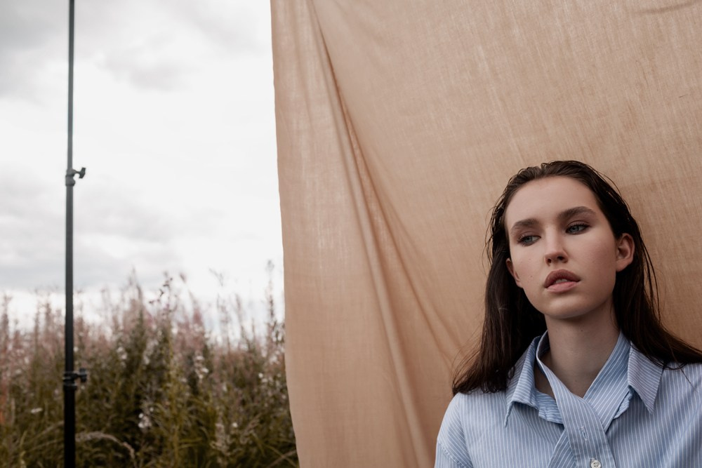 Девушка на природе на фоне ткани в синей рубашке