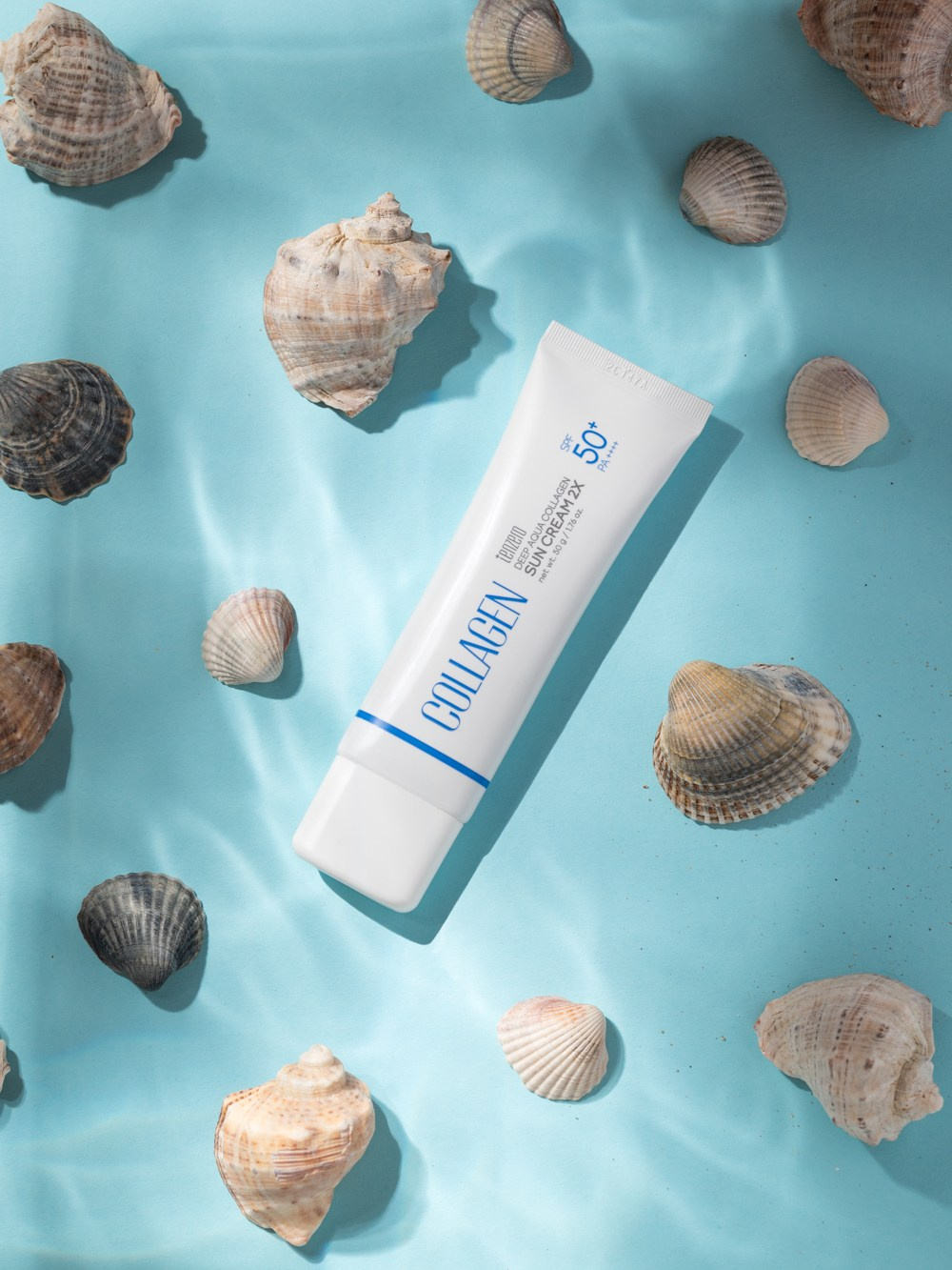 тюбик крема на морском дне в ракушках с волнами от воды