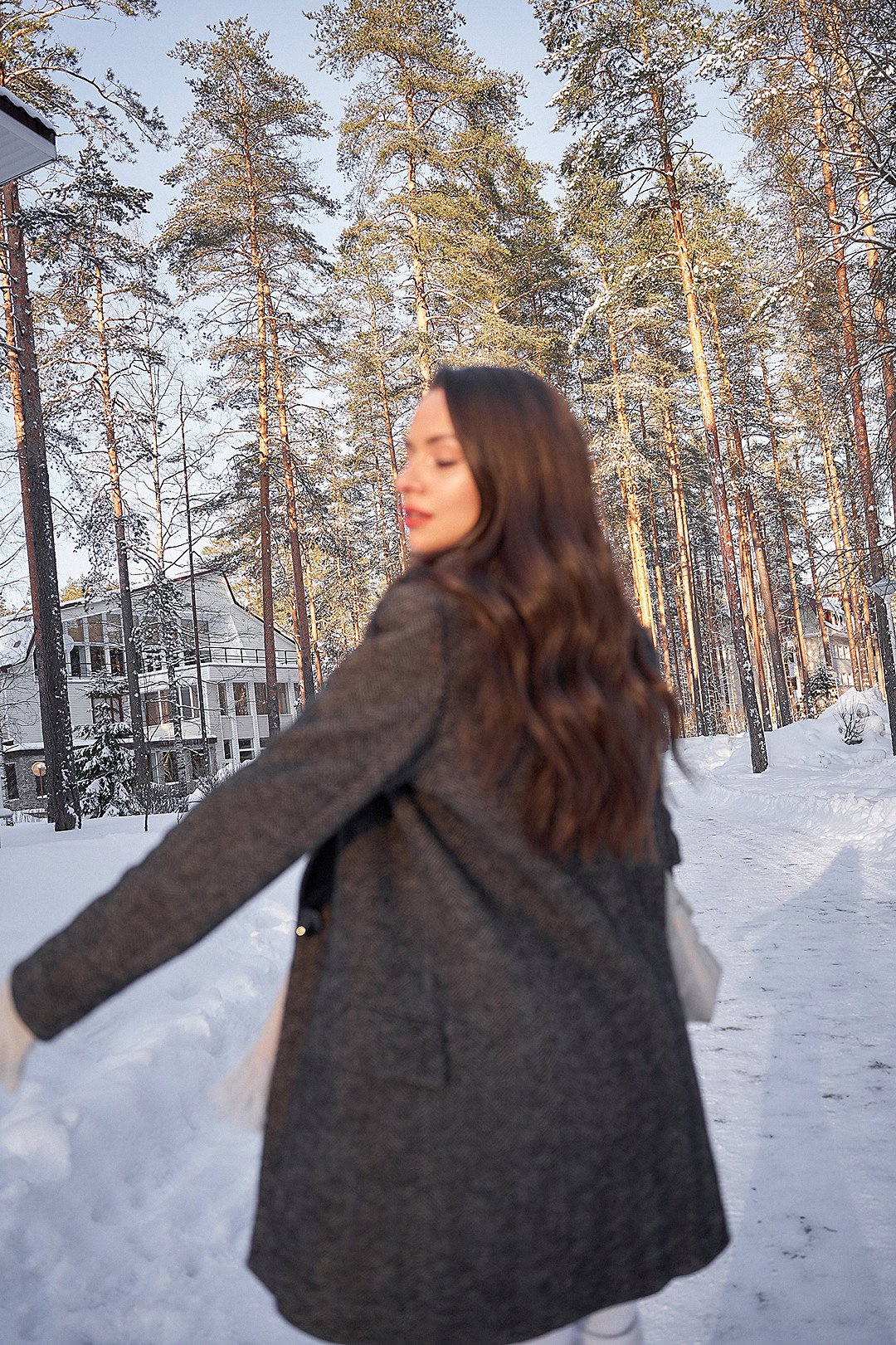 Фэшн портрет девушки в пальто в снежном лесу на закате