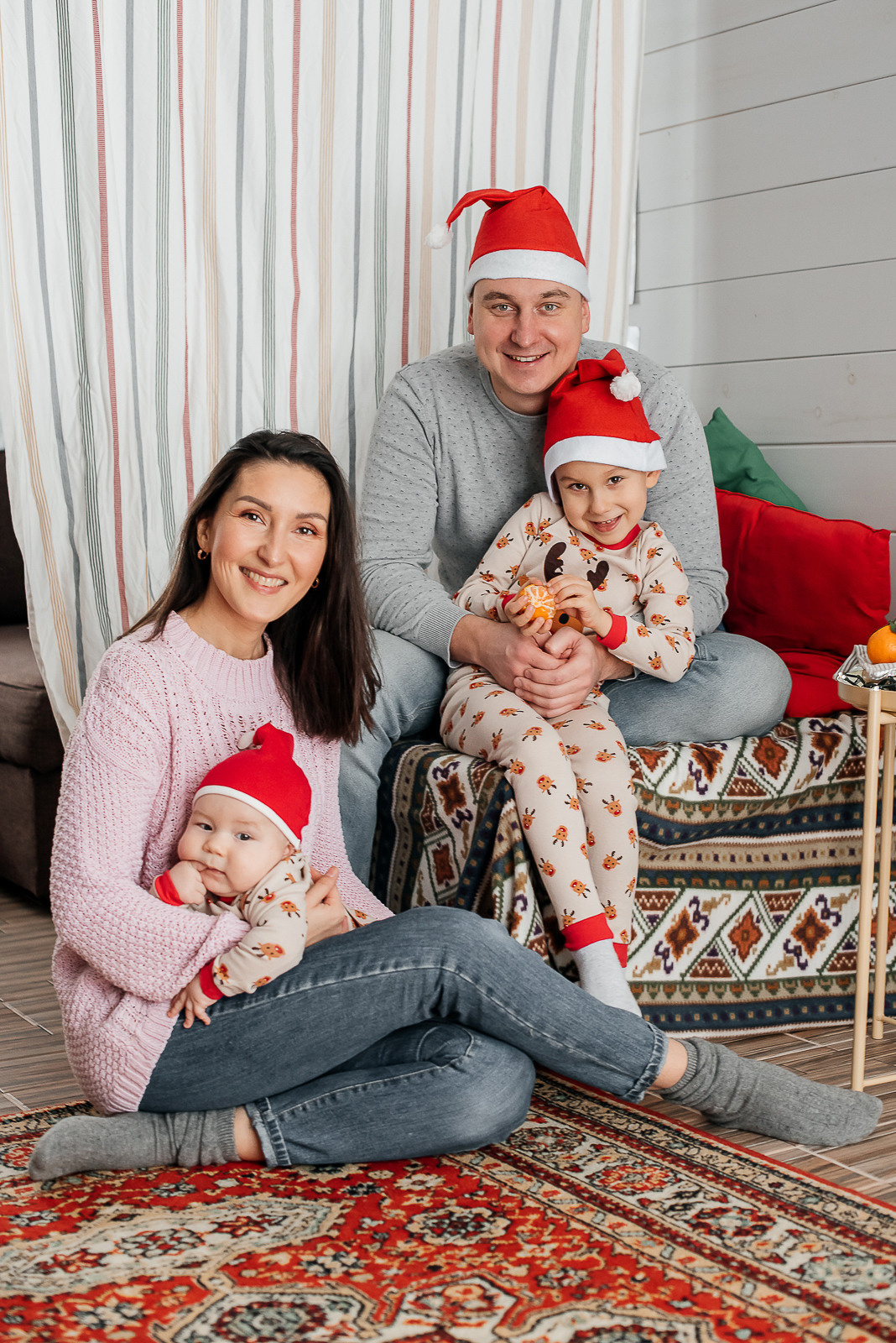 Папа, мама и два сына в пижамах и новогодних колпаках