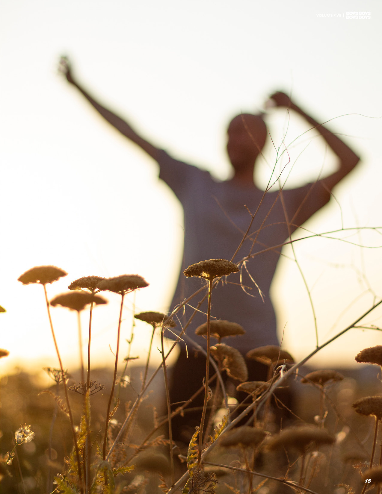 Размытый силуэт мужчины который танцует в лучах закатного солнца в поле пижмы