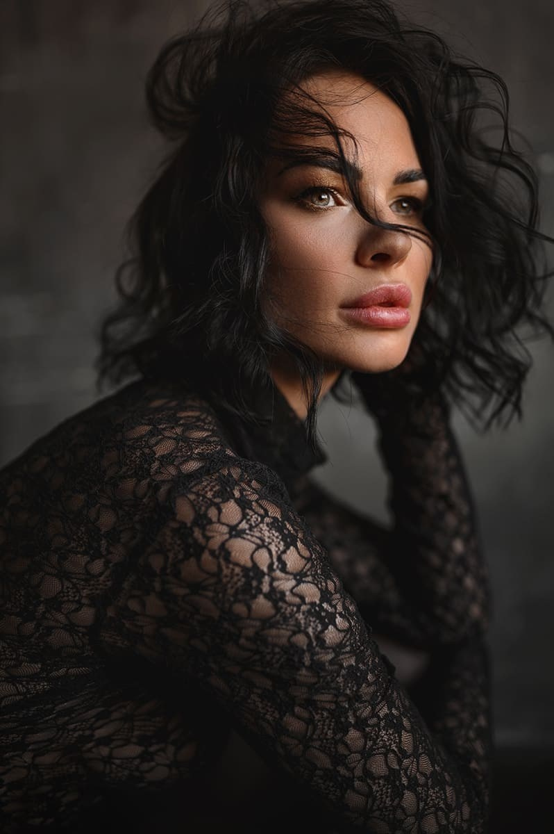 Девушка в чёрном кружевном топе смотрит через плечо