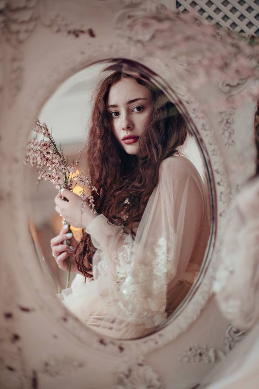 рыжая девушка смотрит в зеркало 