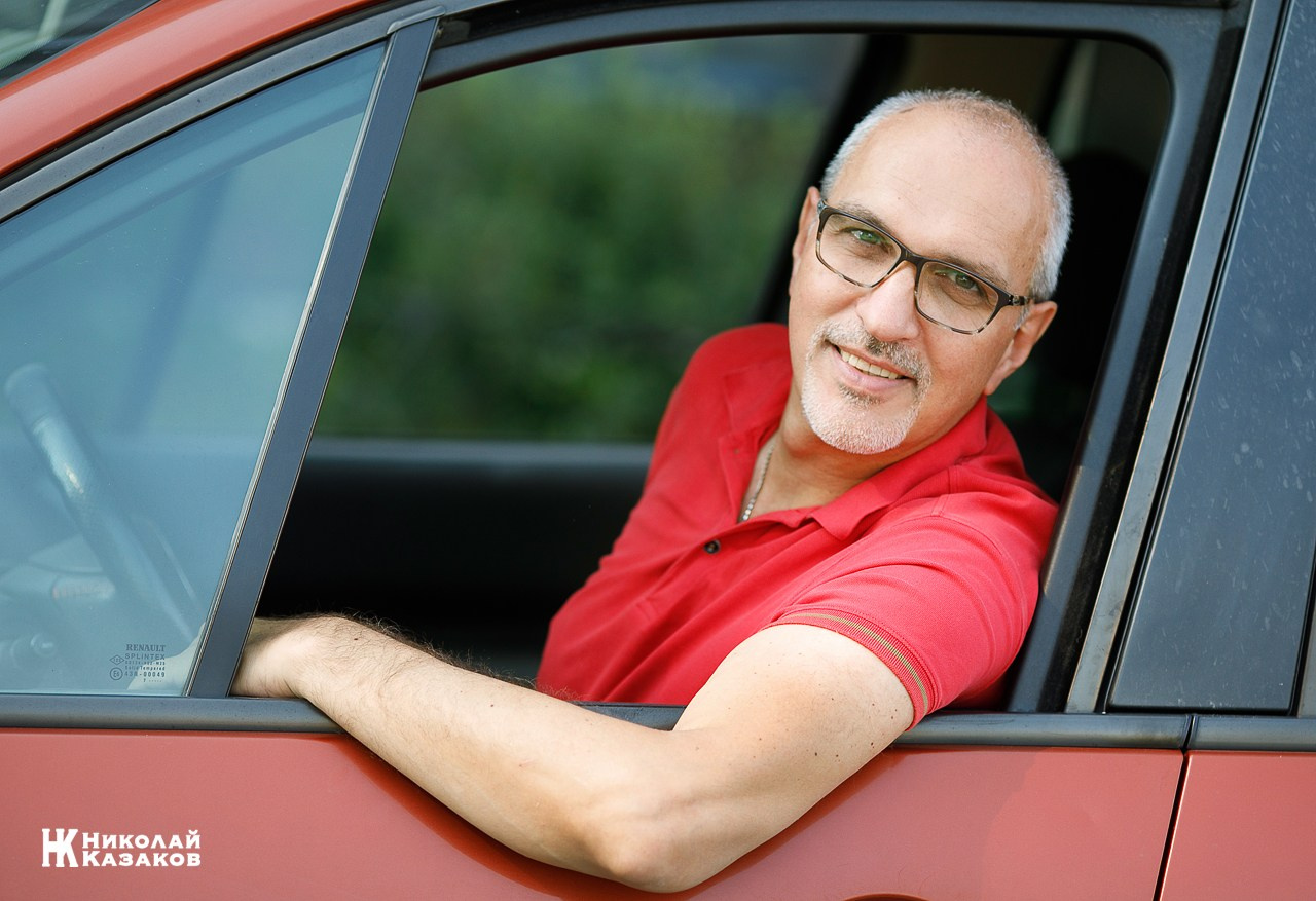 Портрет улыбающегося мужчины в окне своего автомобиля