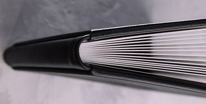 Вид на торец фотокниги в черной коже с выраженной фактурой. Качественная проклейка блока и безупречная геометрия ручной сборки.