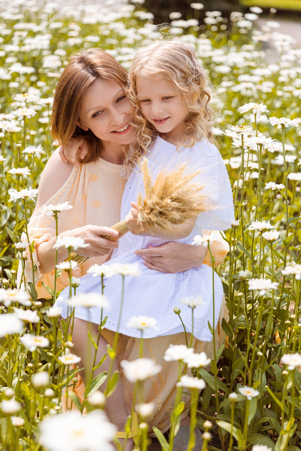 Мама в правой руке держит цветы, левой рукой  обнимает дочь.