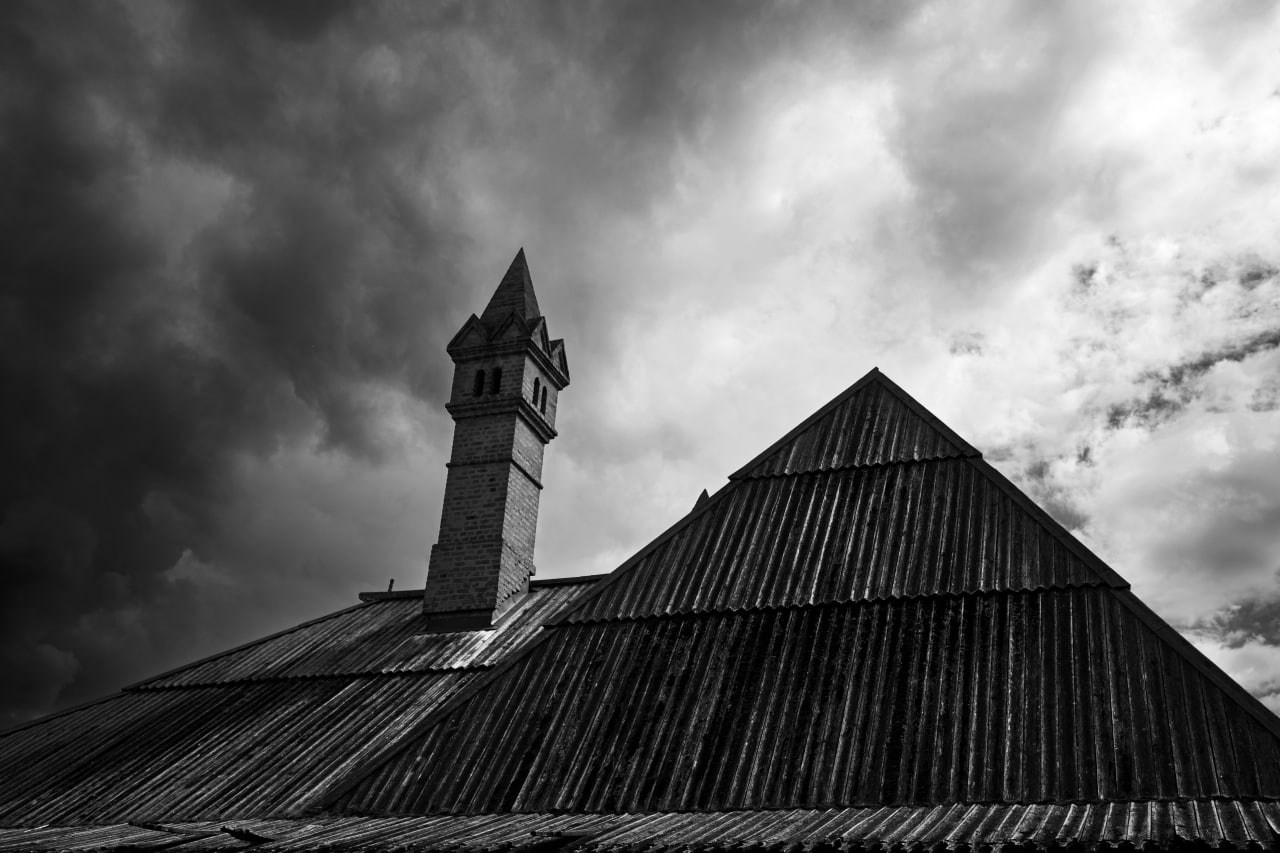 Черно-белая архитектурная фотография: минарет мечети и остроконечная крыша с вертикальными складками на фоне драматичного облачного неба, контраст света и тени, геометрия сакральной архитектуры, уличная фотография Москвы, Вадим Топорёнок, проект Манифест теней, городская духовность, вертикали веры, монохромная архитектура, исламская архитектура в городе.