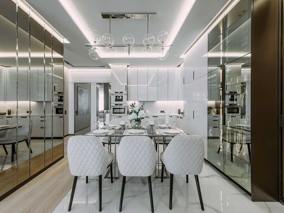 Кухня-столовая с зеркальными фасадами, белыми шкафами и дизайнерским светильником | Валерия Котович