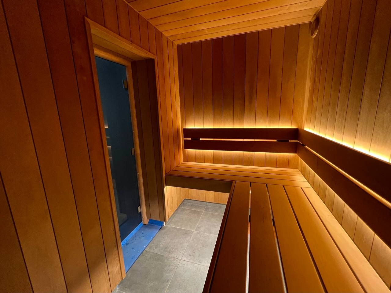 Уютная парная в Колтушах: внутренняя топка, печь в редкой облицовке, термоольха и тёплая линейная подсветка. SaunaTopMasters