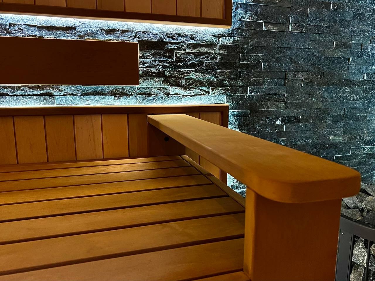 Просторная сауна в Сертолово из термоольхи с интеграцией можжевеловых линий и большого количества натурального камня. SaunaTopMasters