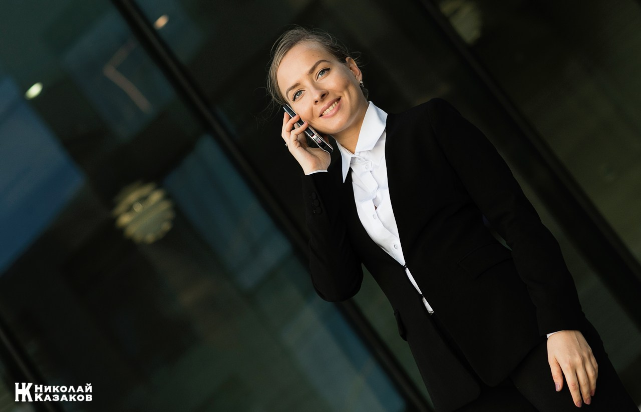 Портрет уверенной деловой женщины со смартфоном во время фотосессии.