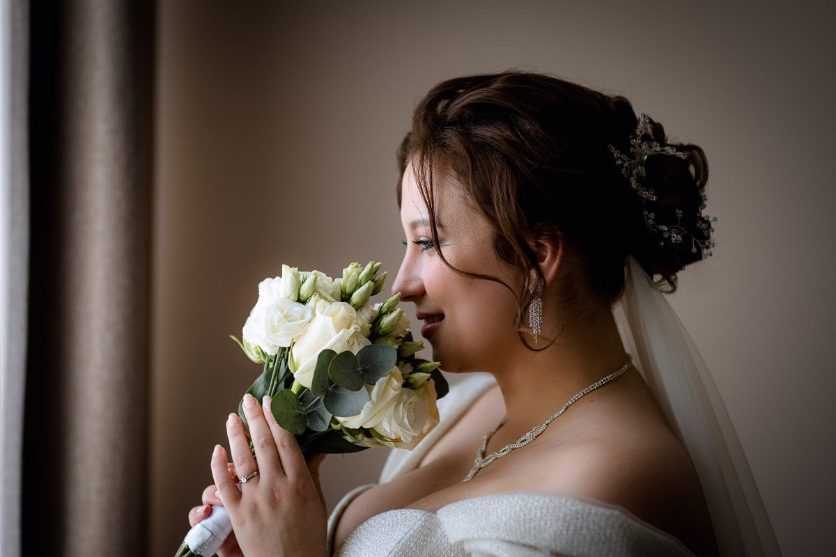Невеста у окна нюхает букет. Крупный план горизонтальный