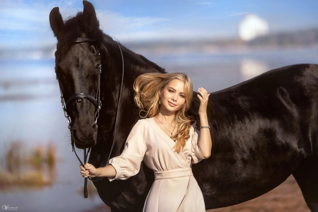 Красивая девушка рядом с вороной лошадью