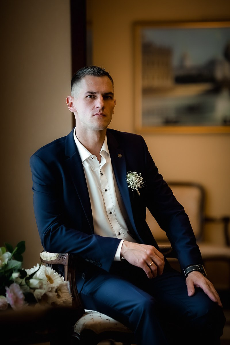Жених сидя смотрит в кадр в ЗАГСе на Васильевском острове в Санкт-Петербурге. Вертикальный кадр.