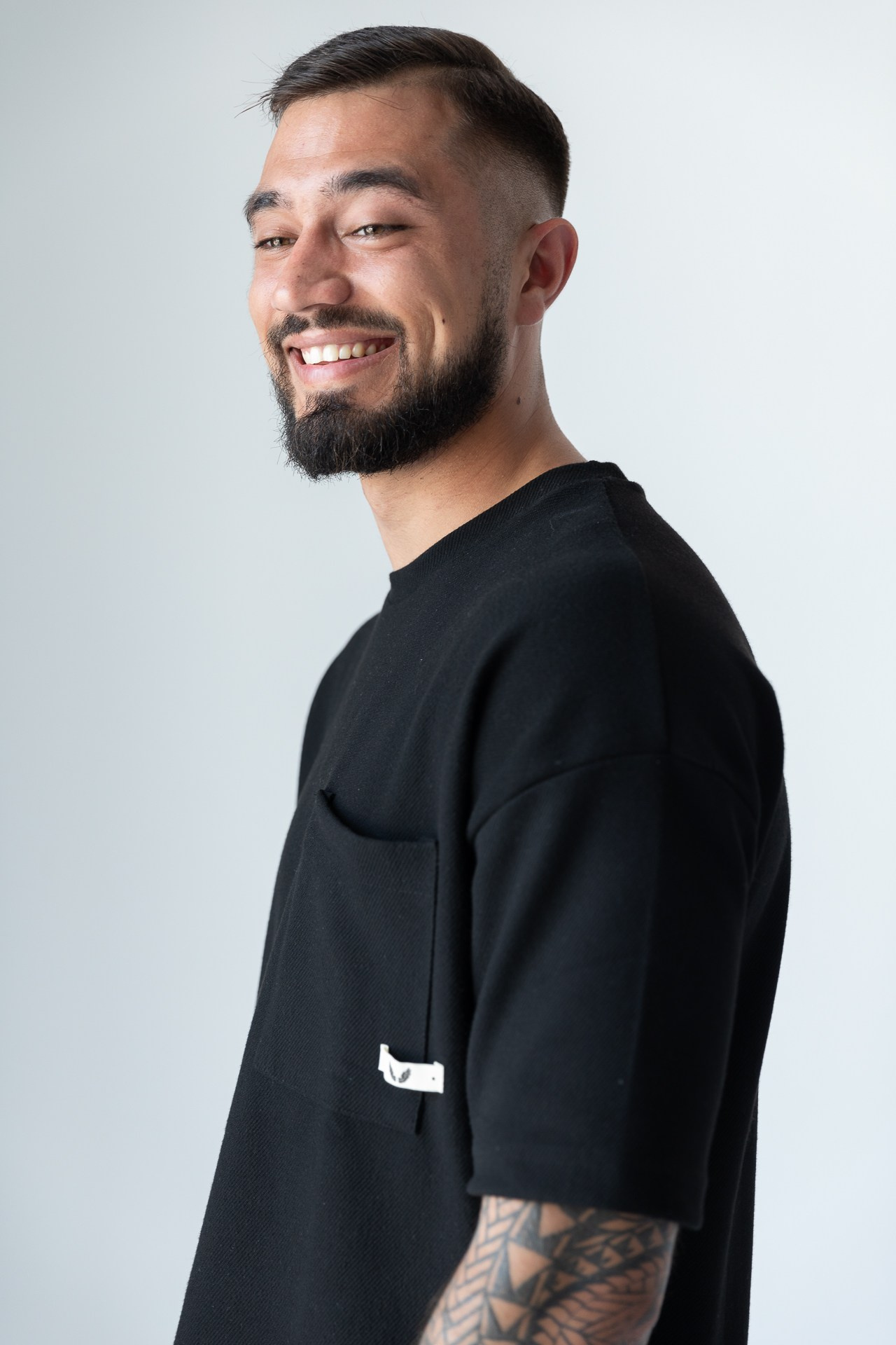 Мужчина с бородой в черной футболке улыбается