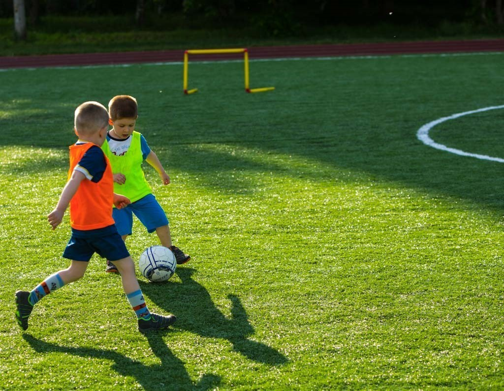 Ребенок ведет мяч по линии на детской футбольной тренировке