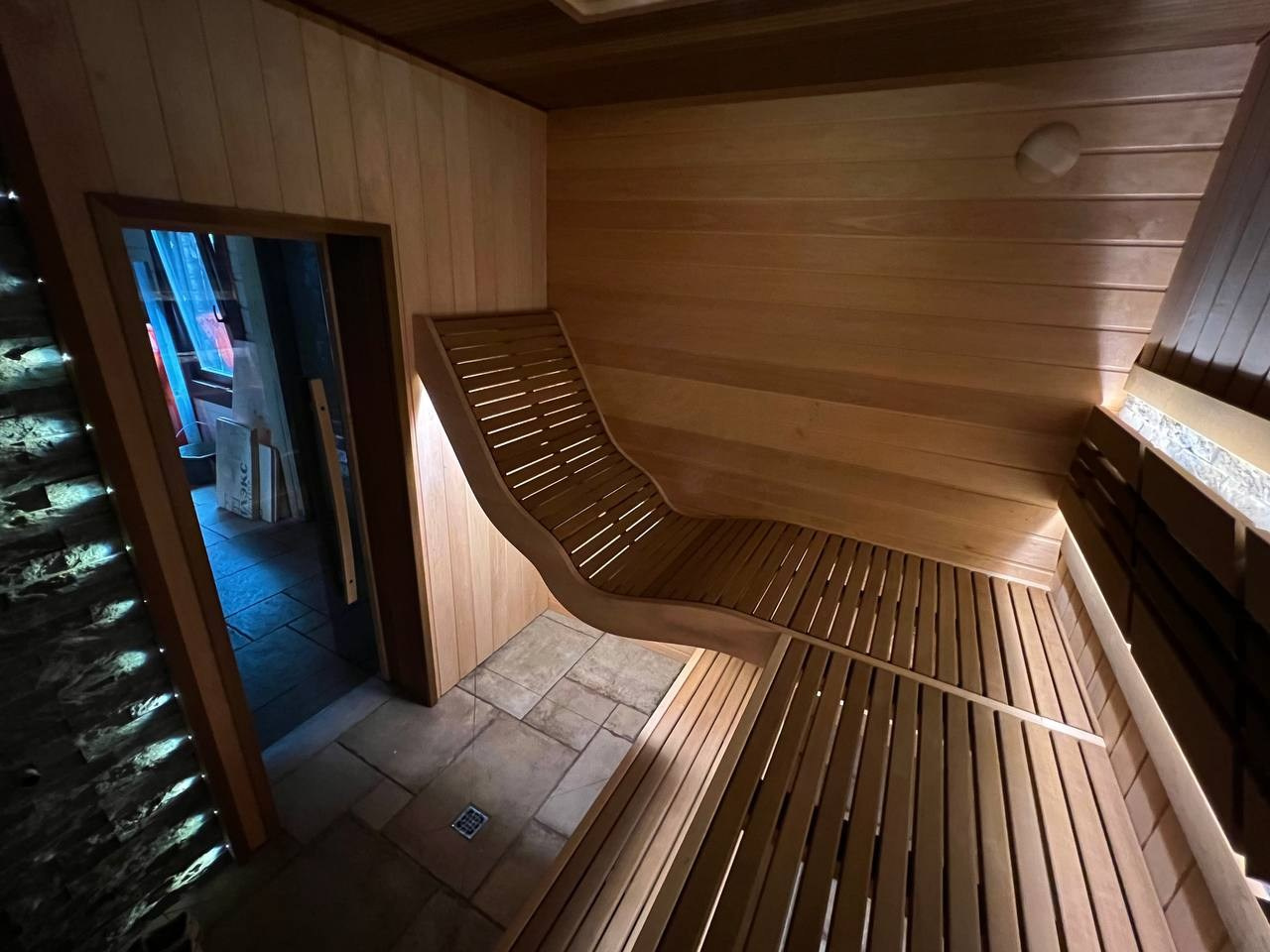 Парная в Лисьем носу с анатомическим пологом и можжевеловым панно, а хромированная печь в свете оптоволокна создает неповторимую атмосферу. SaunaTopMasters