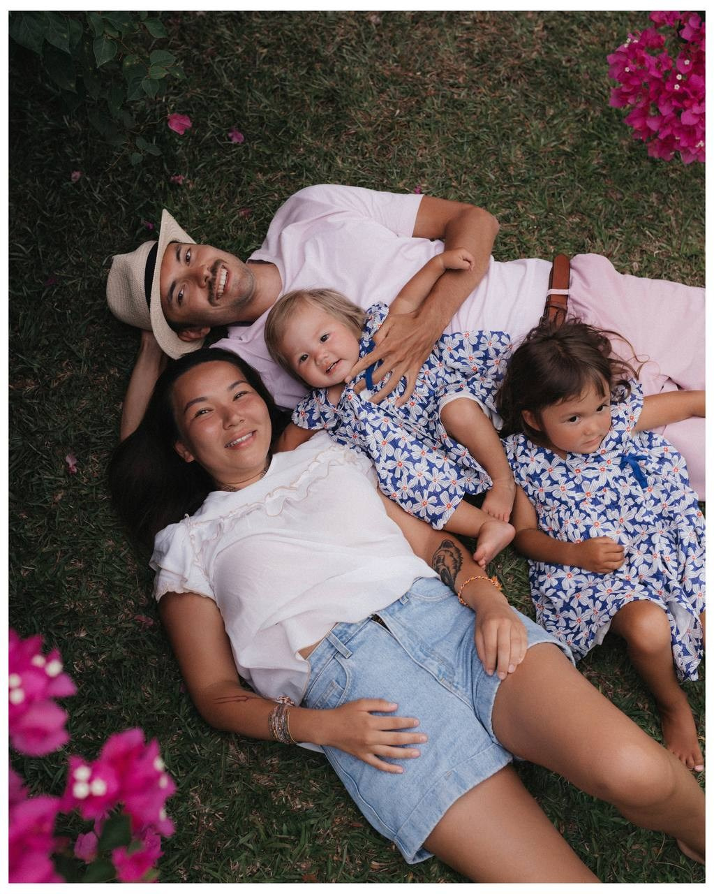 Семья лежит на траве среди цветов, уютный общий кадр