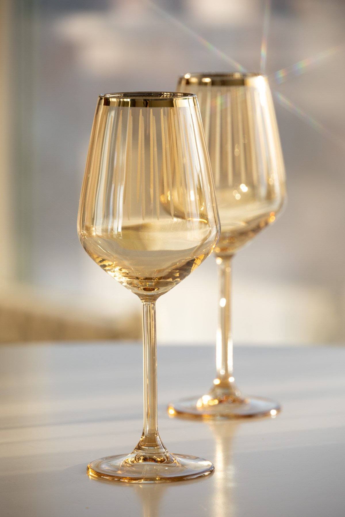 Прозрачные бокалы золотистого цвета на столе | Фото с переливами для каталога посуды