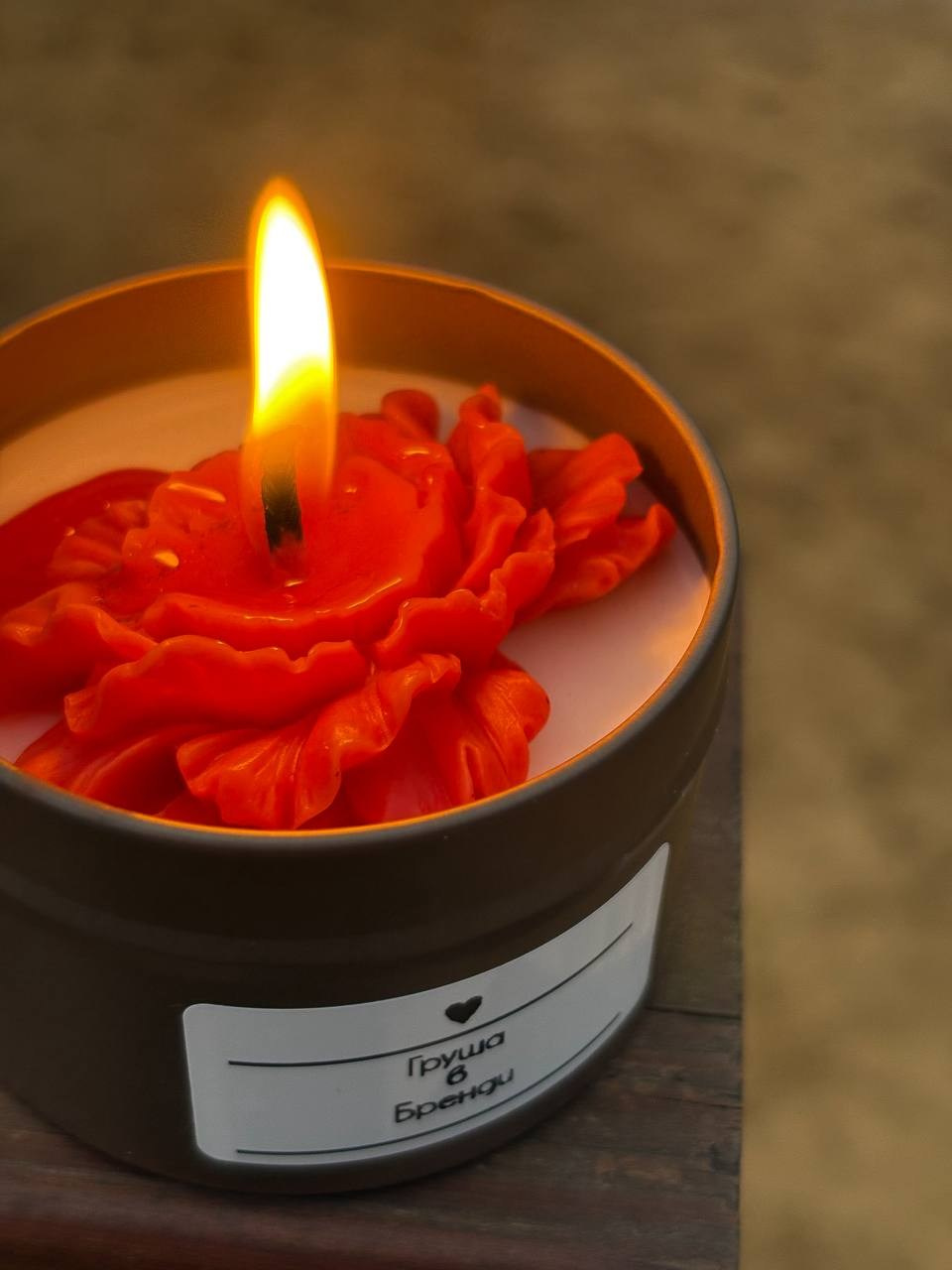 Фото горящей красной свечи в тёмной банке — предметная съёмка.