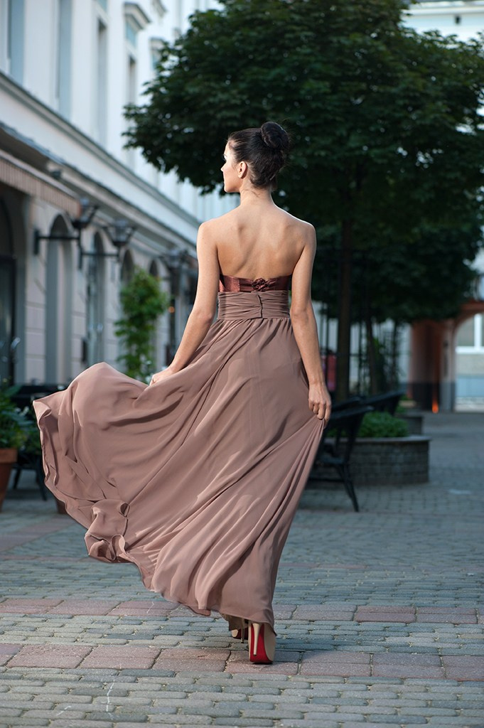 Модель в летящем платье на городской улице.