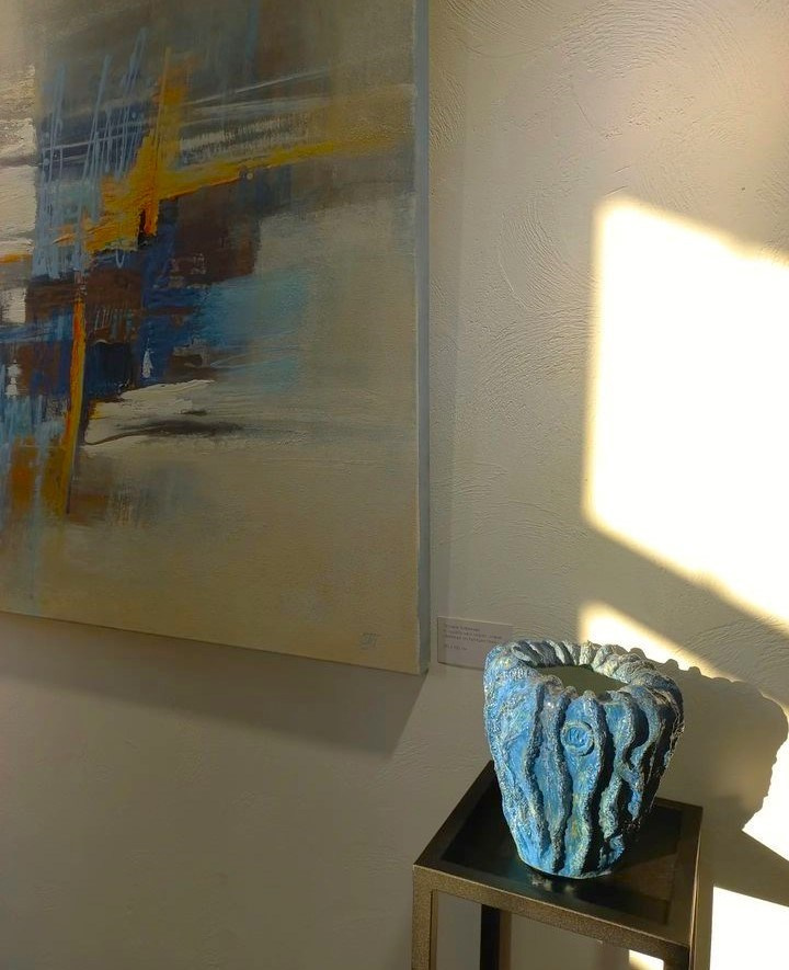 Голубая керамическая ваза рядом с картиной