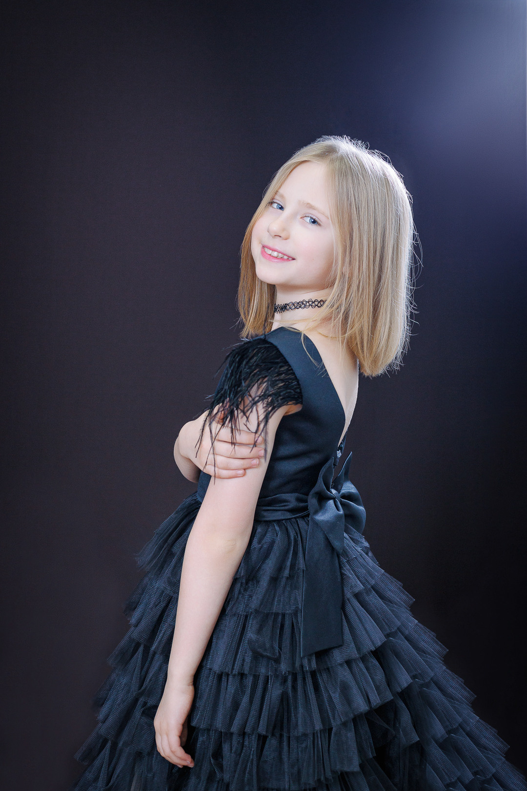 Девочка в черном платье позирует для конкурса красоты