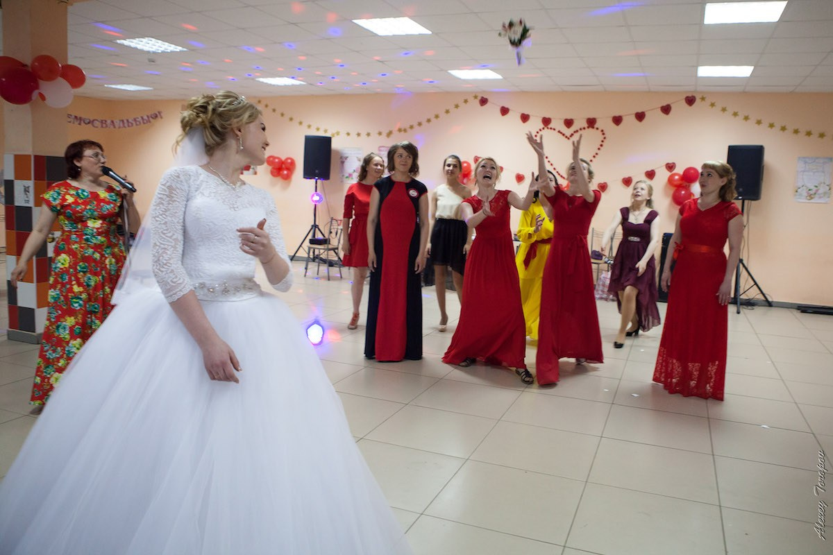 Яркая группа гостей и молодожены смеются во время активного свадебного конкурса