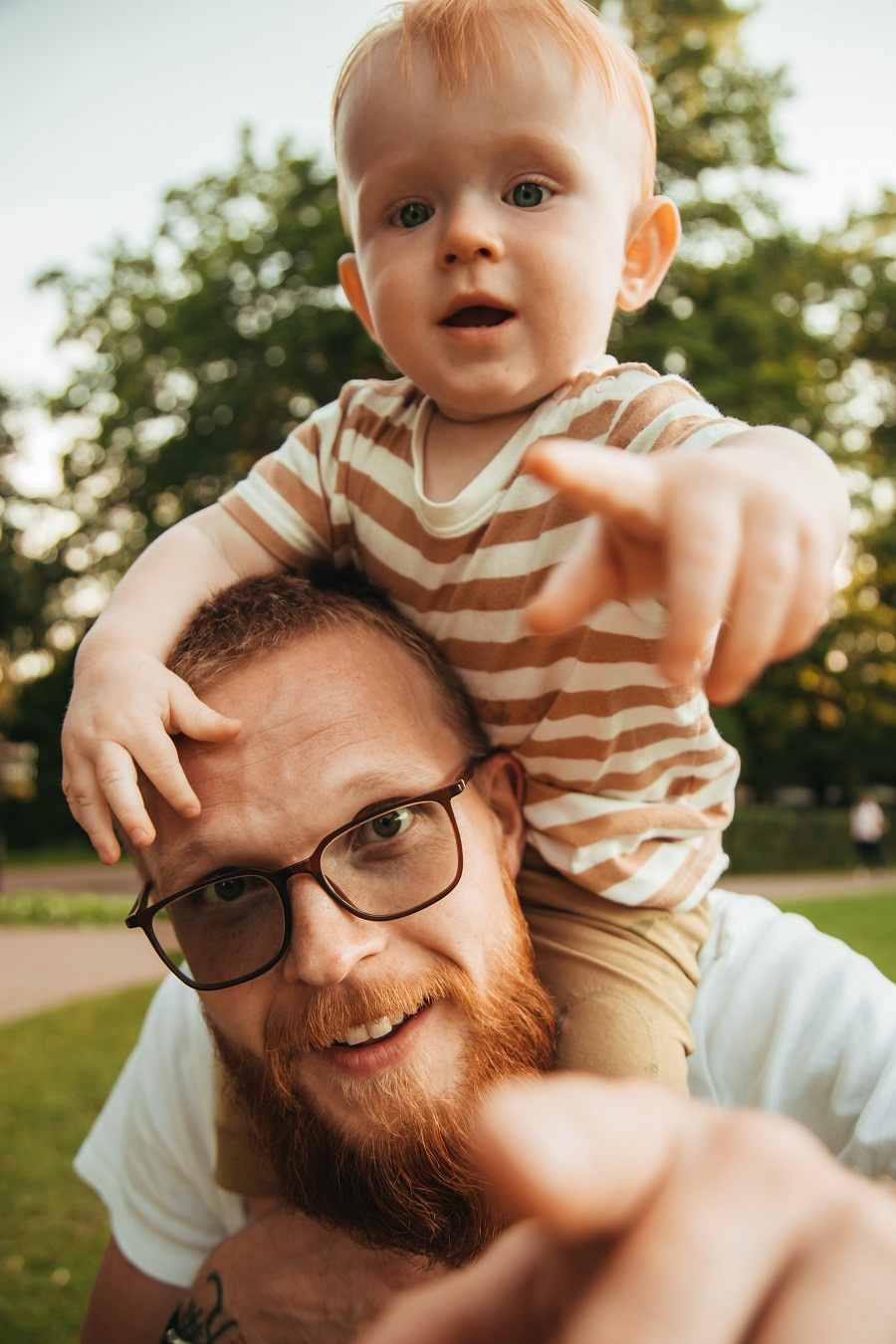мужчина в белой футболке несет на плечах ребенка