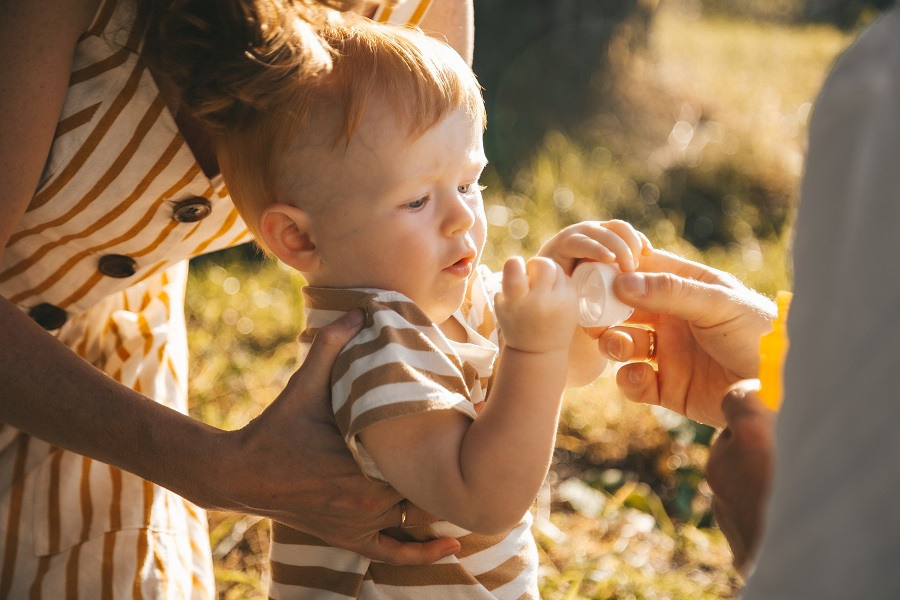 Мама держит малыша, а он дует мыльные пузыри