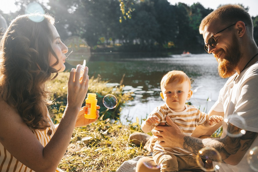 семья у пруда дует мыльные пузыри
