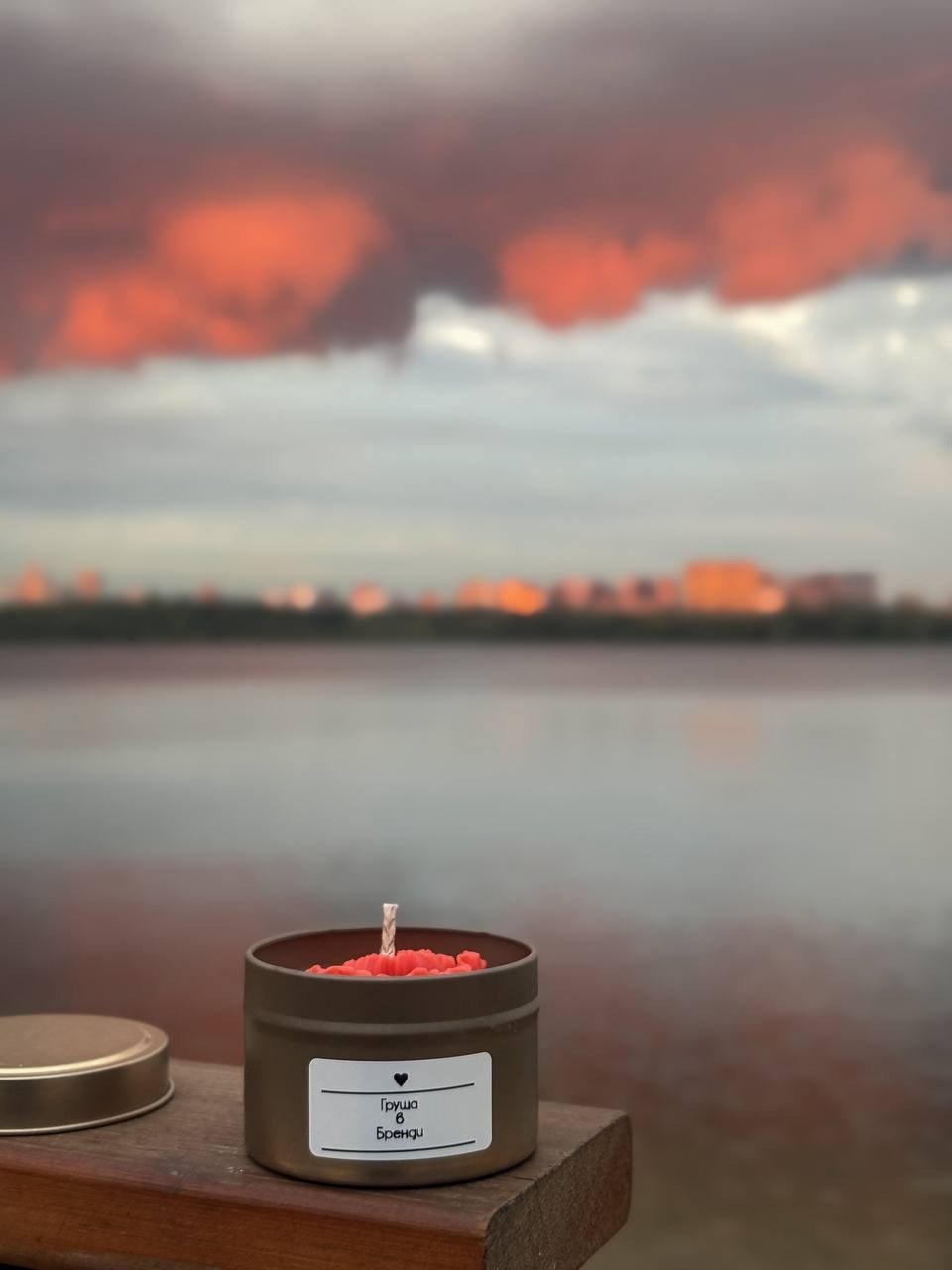 Мини-съёмка свечи в баночке на фоне розового заката у воды.