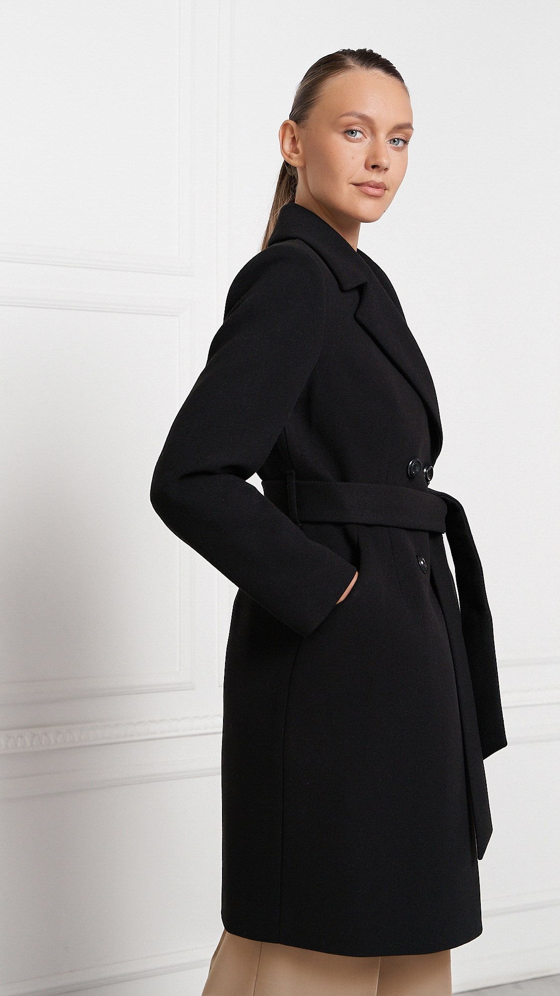 Красивая девушка в пальто позирует на камеру