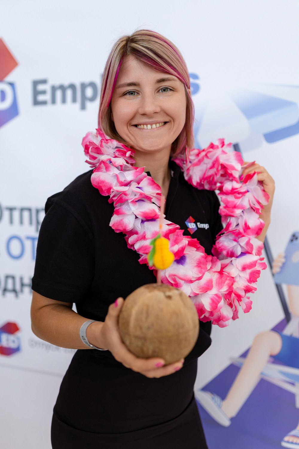 Женщина стоит на фоне прессвола держит в руках кокос