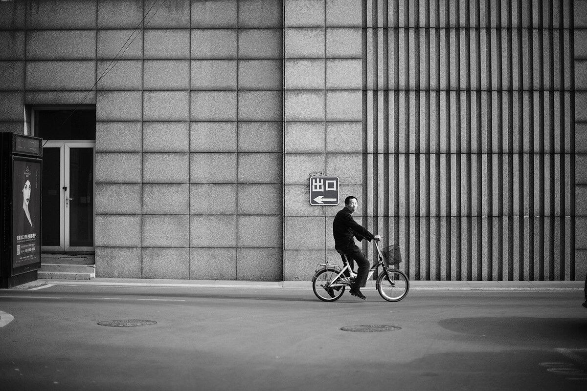 Китаец на велосипеде  едет по улице