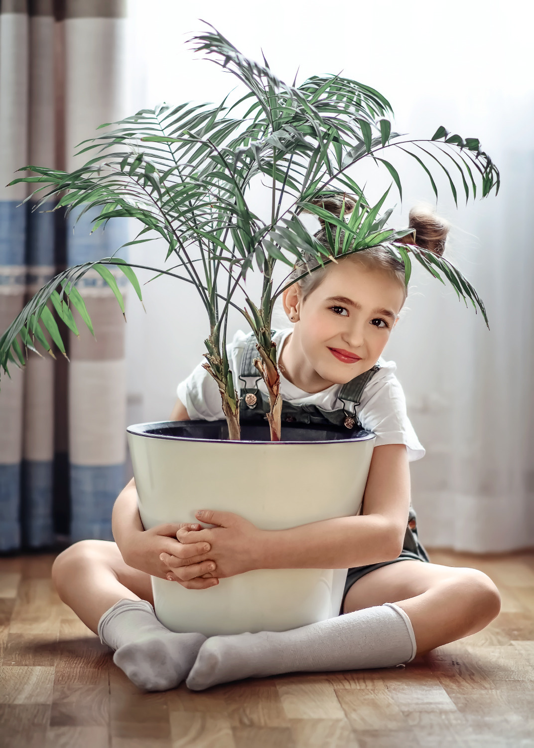 Ребенок обнимает комнатное растение.