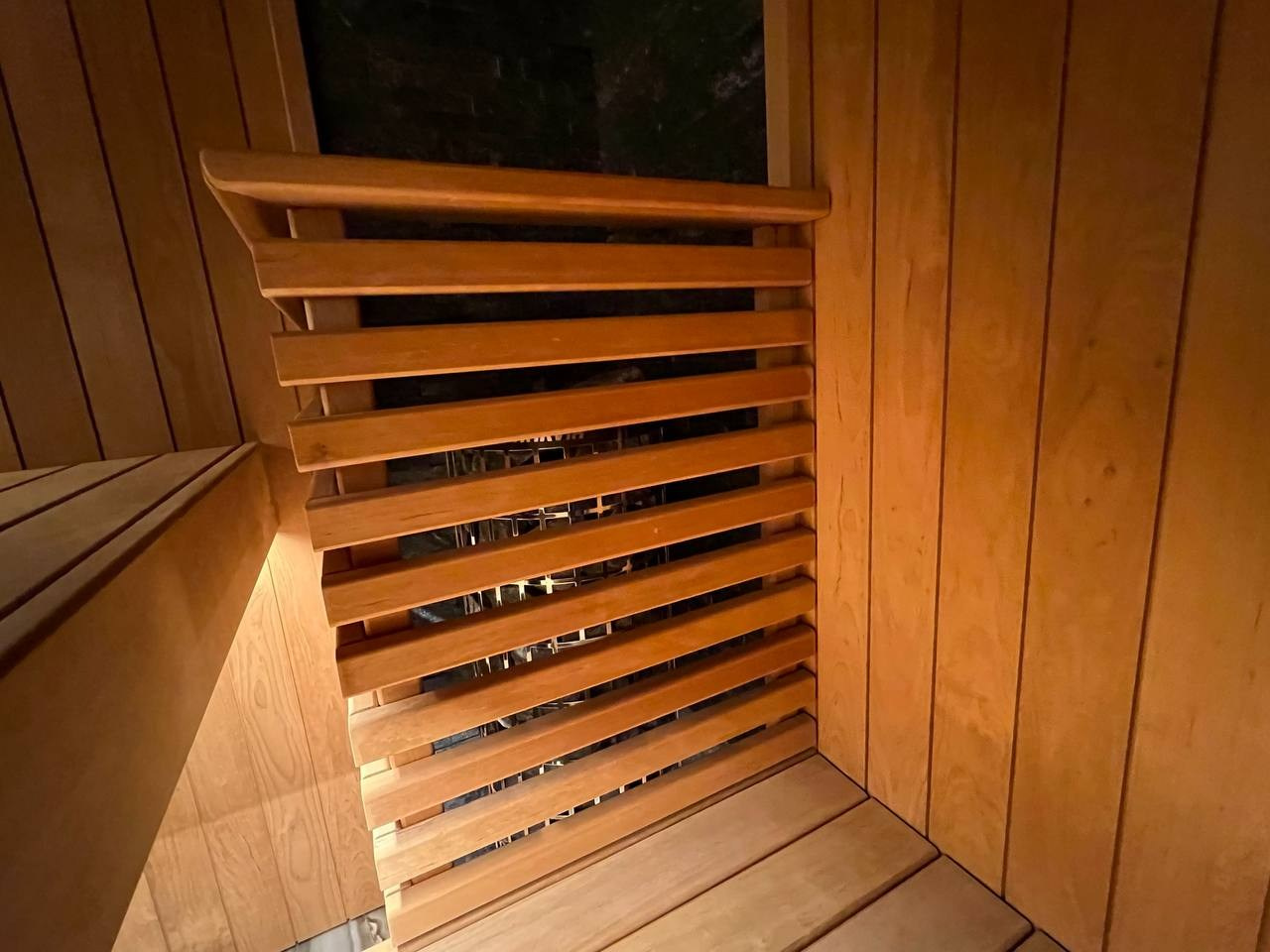 Семейная сауна в Охте: термоольха, природный камень и аккуратное реечное ограждение печи, защищающее любопытные детские ручки. SaunaTopMasters