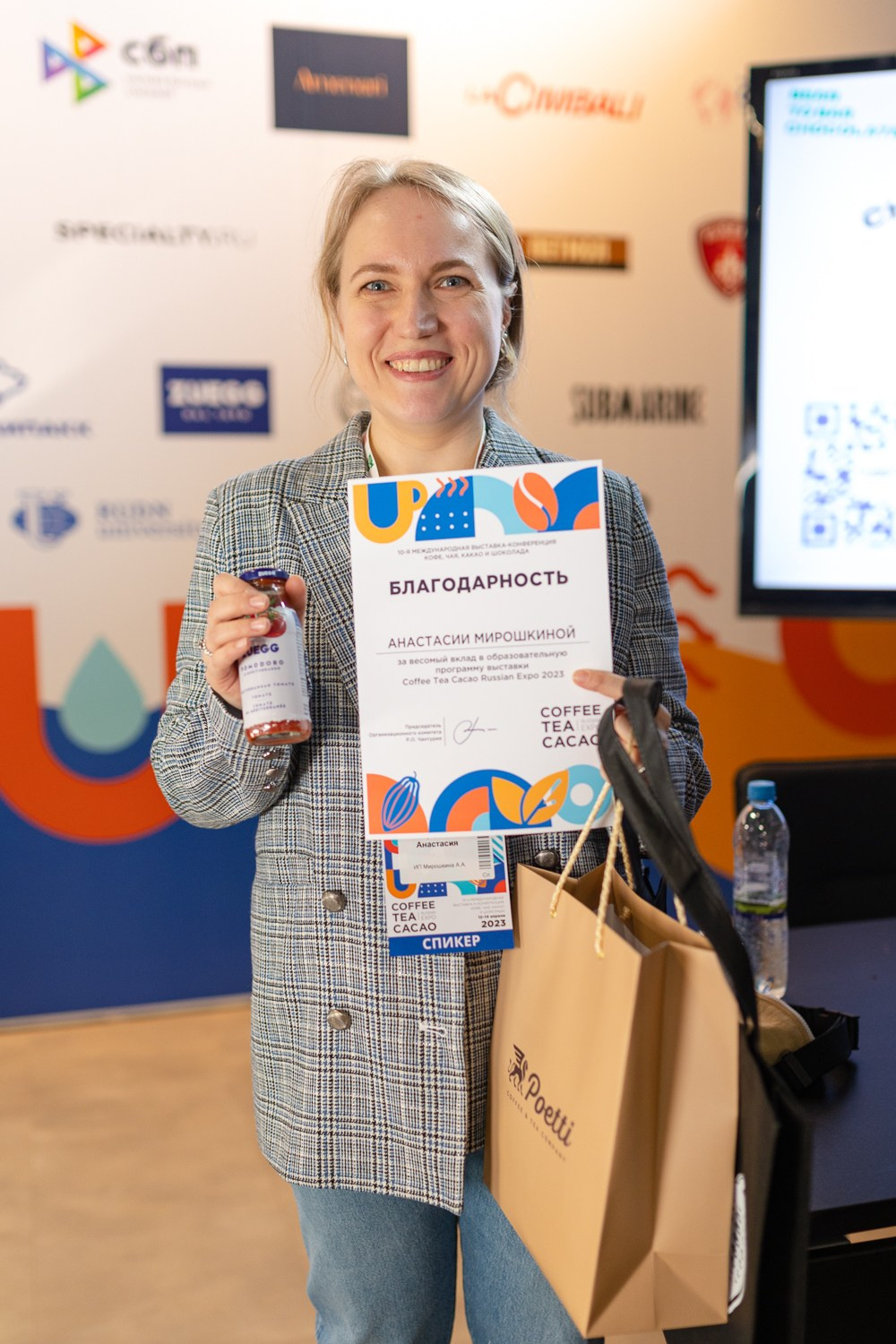 Девушка стоит с наградой и памятными подарками в руках после лекции