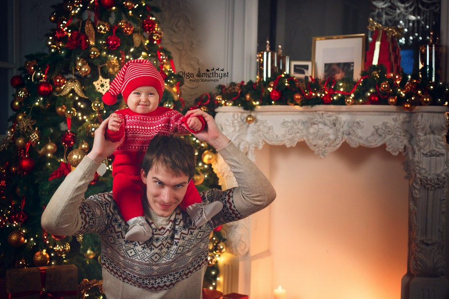 Папа и маленький ребенок позируют на фоне новогодний елки.