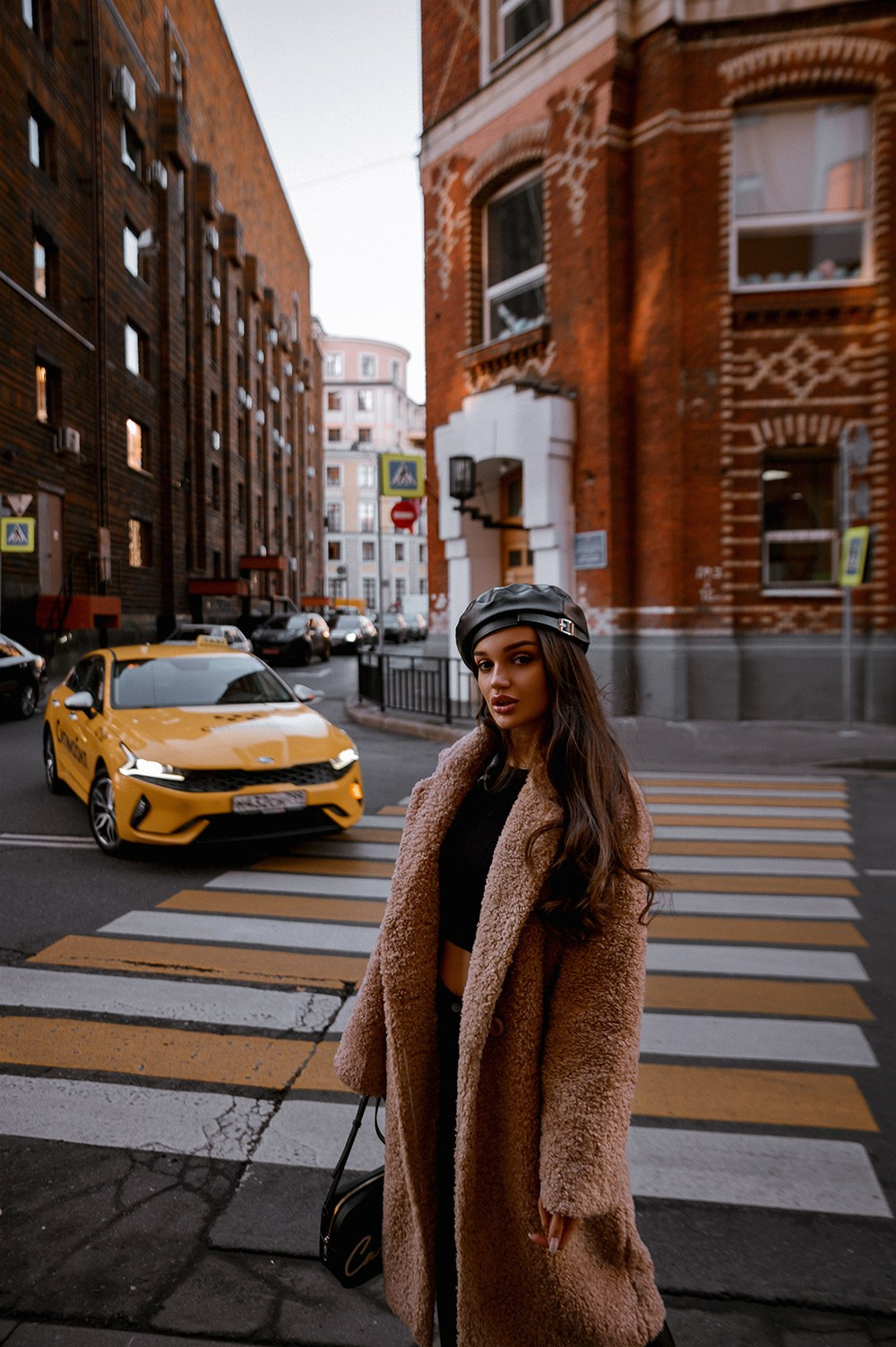 Женщина в пальто переходит улицу с такси