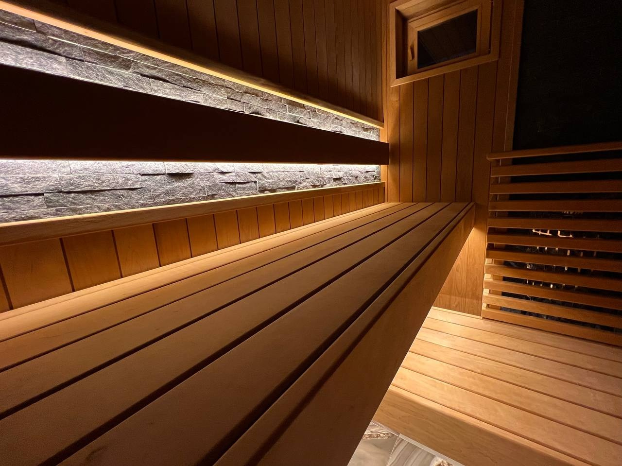 Семейная сауна в Охте: термоольха, природный камень и аккуратное реечное ограждение печи, защищающее любопытные детские ручки. SaunaTopMasters